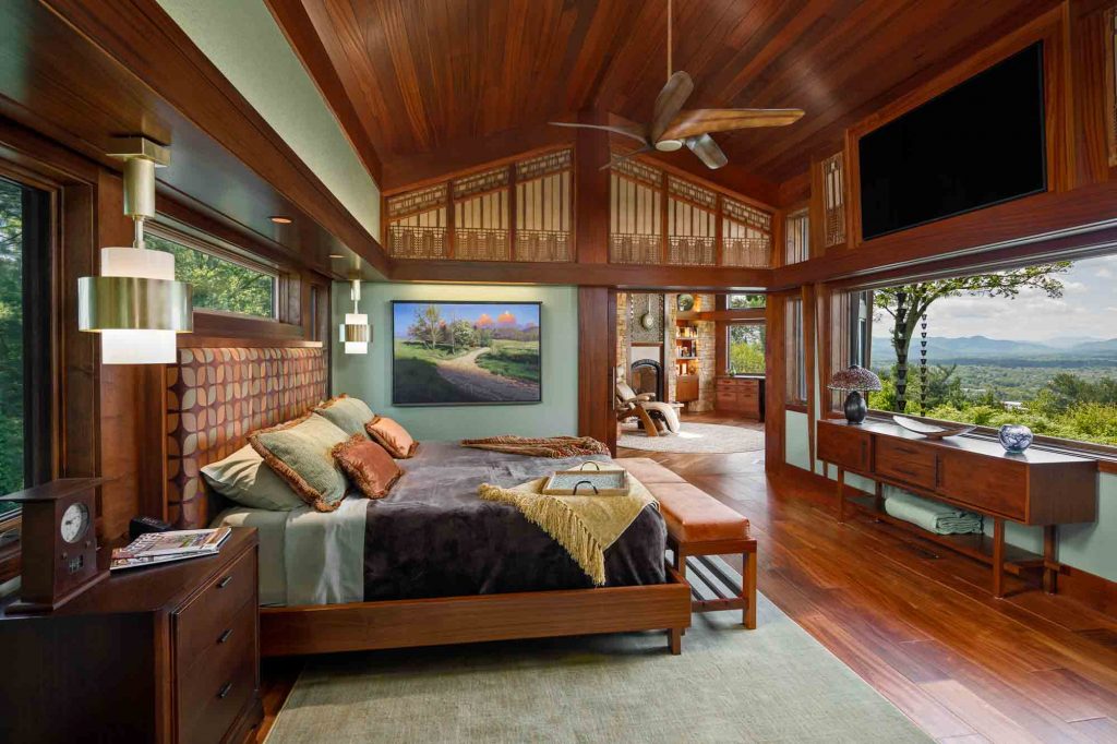 A remodeled bedroom with ornate wood detailing and a picture window overlooking the mountains